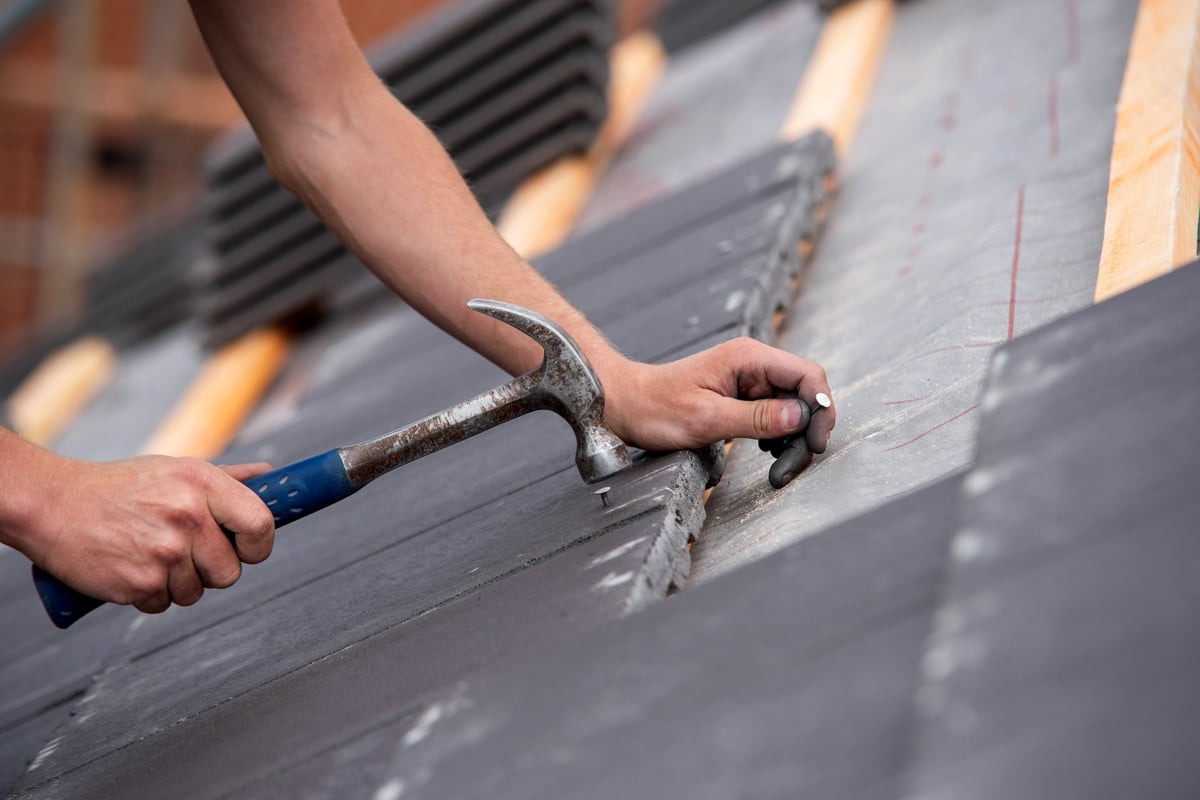Skilled builder installing roofing tiles